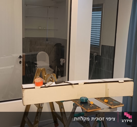סולם, שולחן עבודה, קרטון וכלי עבודה בחדר